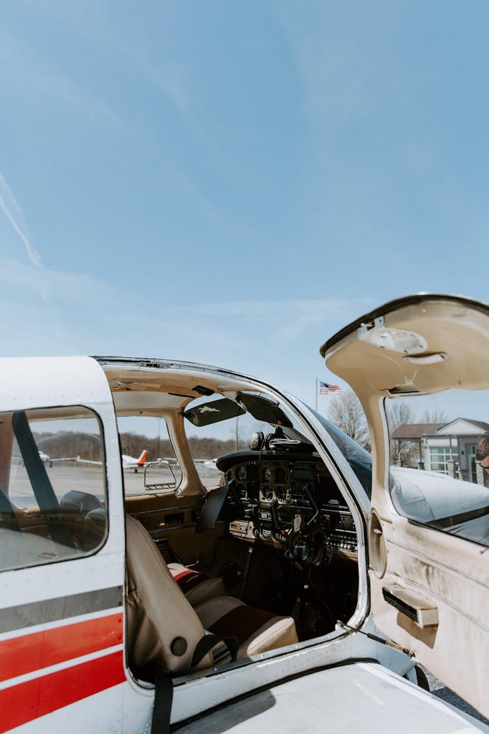 Open cockpit view of a parked small aircraft on a sunny day.