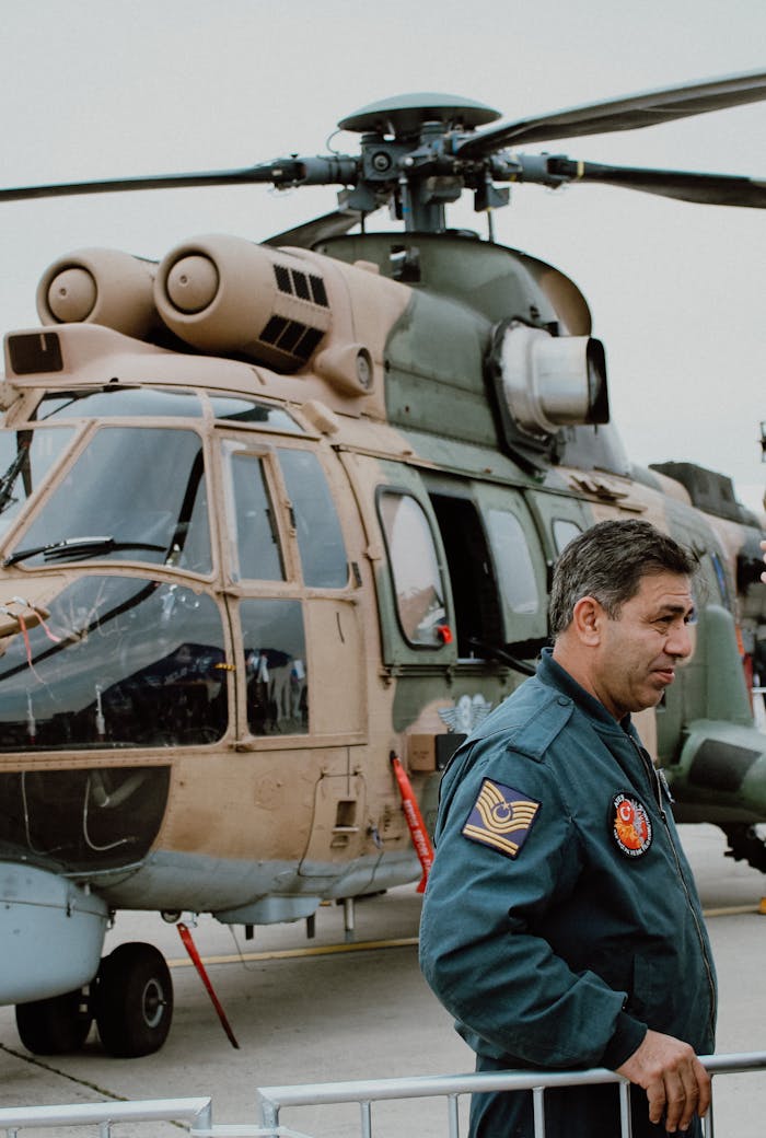 A military pilot beside a helicopter in İstanbul, showcasing aviation and defense.
