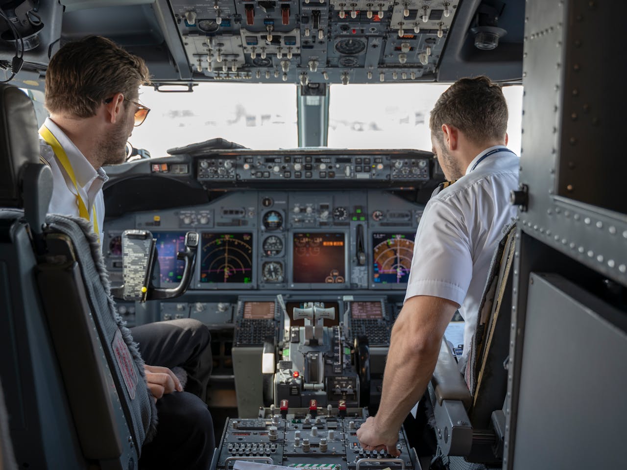 Two pilots navigating an aircraft cockpit, focused on advanced avionics and flight systems.