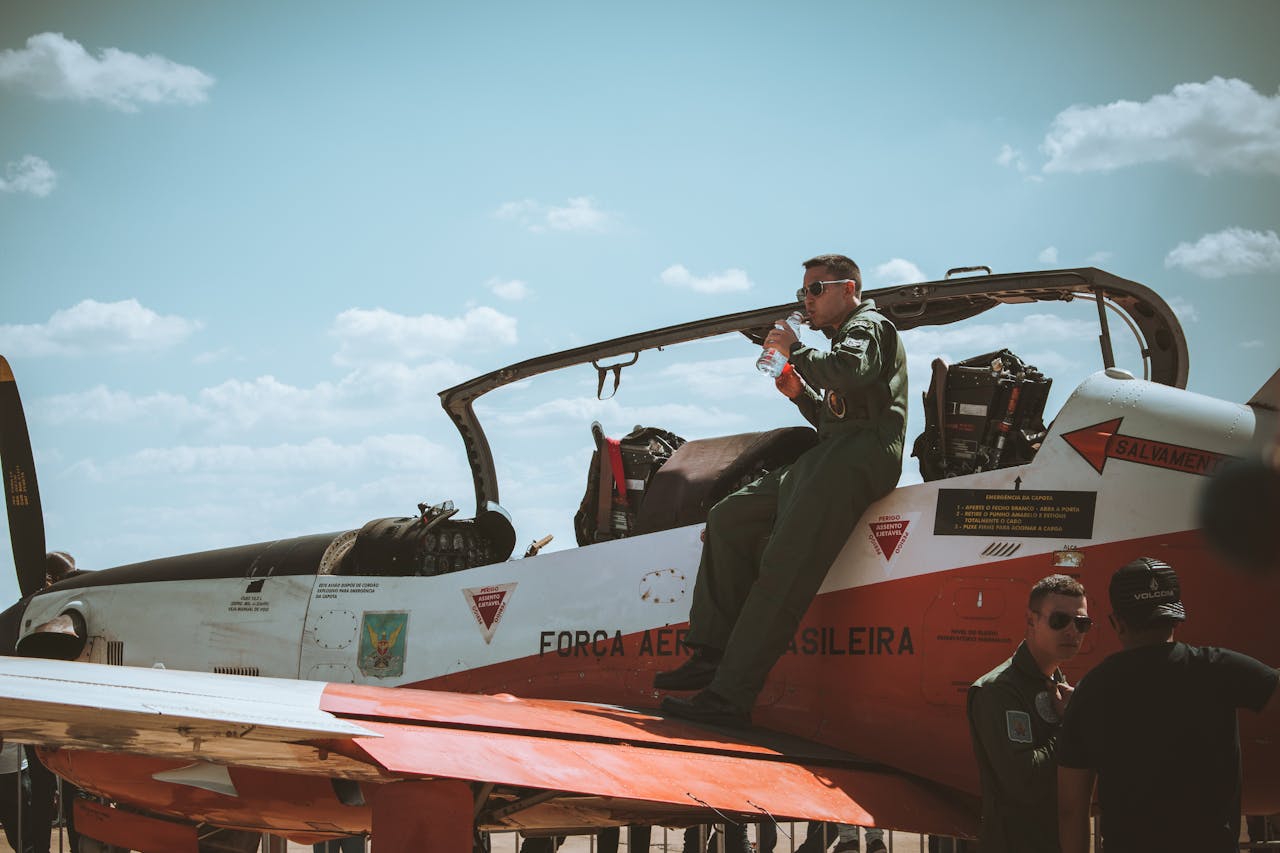 A Brazilian Air Force pilot resting on a fighter jet wing, illustrating aviation and military life.