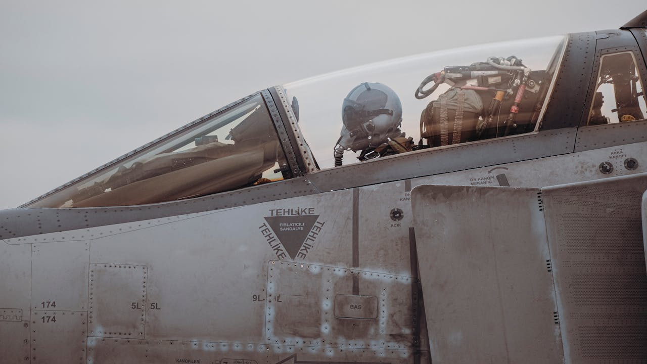 A detailed view of a military jet fighter's cockpit with a pilot, showcasing aviation technology.